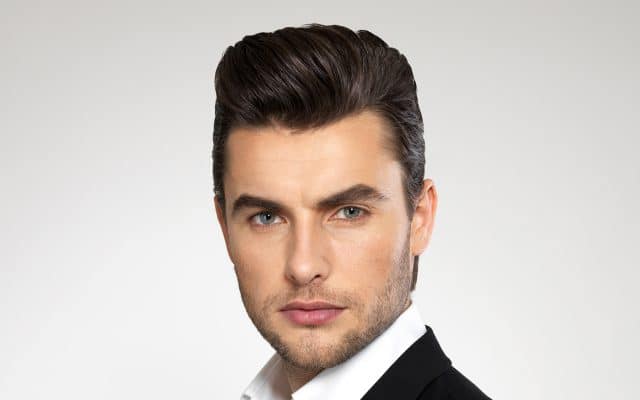 Ein Herren-Model mit einem modischen Haarschnitt schaut den Nutzer an